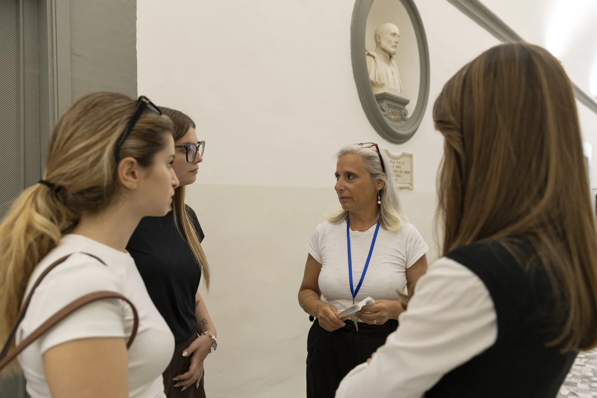 Uma docente conversa com quatro alunas no corredor do campus