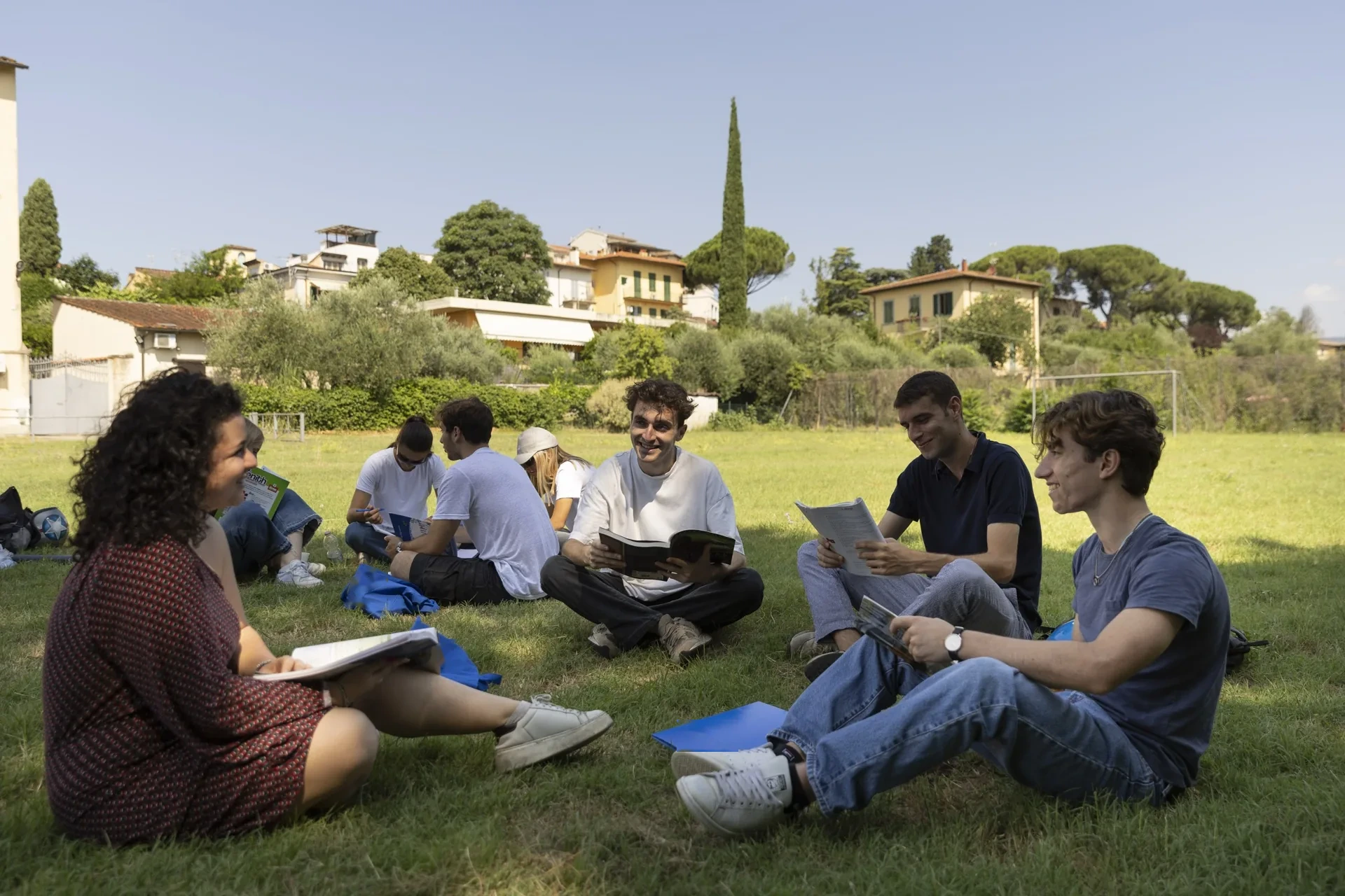 Students sitting on the lawn of the Florence campus, with books and notes